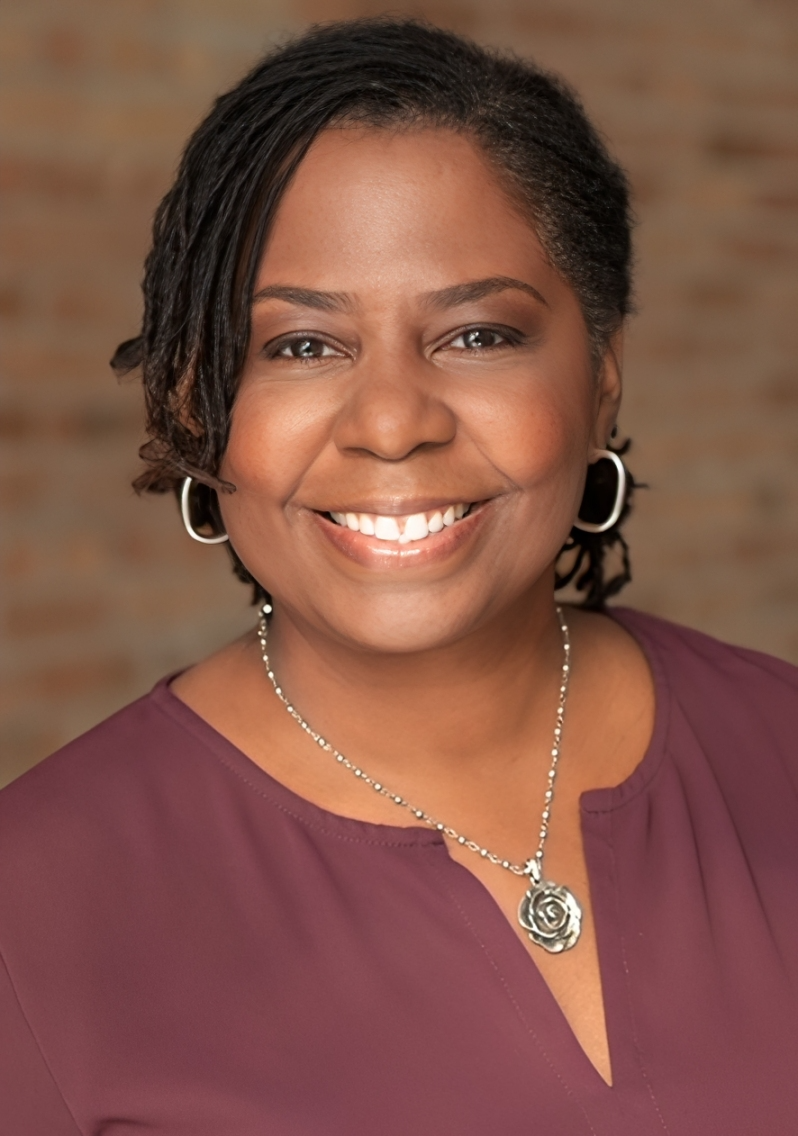 Smiling woman with necklace and hoop earrings.